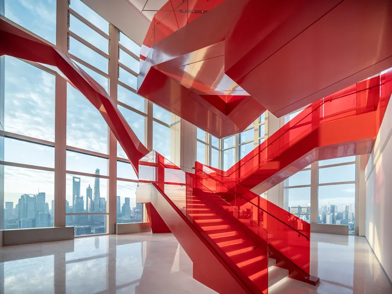 Double-height interior staircase wrapped in translucent red glass with floor-to-ceiling curtain wall beyond
