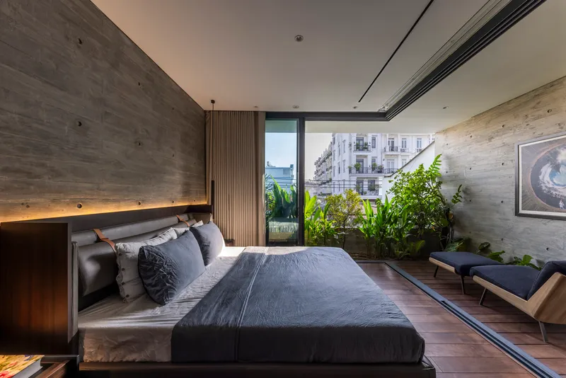 Bedroom with concrete accent wall and sliding doors framing a verdant balcony garden