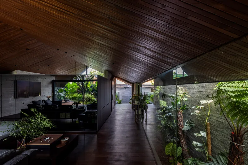 Interior hallway with sloped wood ceiling and glazed walls opening to planted courtyards on both sides