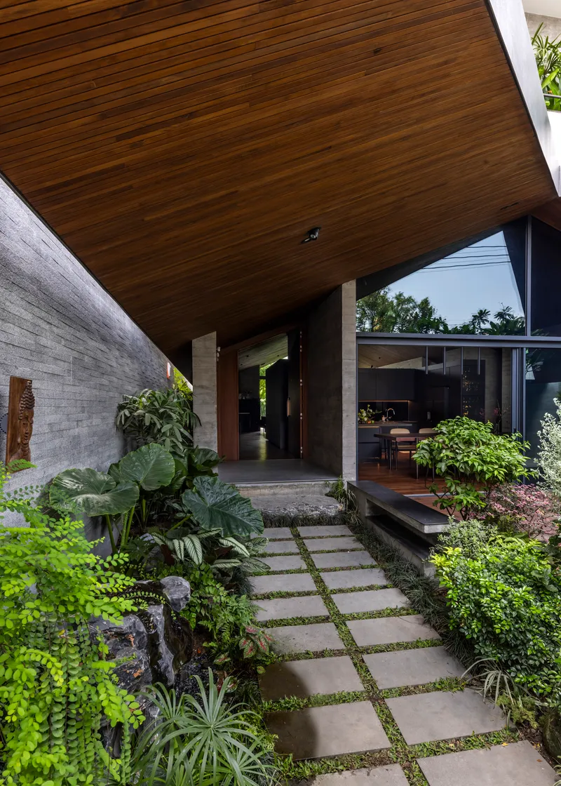 Entry courtyard with stepping stone path through planted beds under a timber-clad soffit