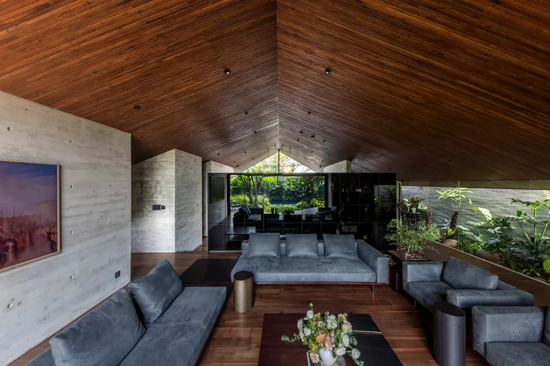 Living room with pitched timber ceiling and board-formed concrete walls framing a courtyard view