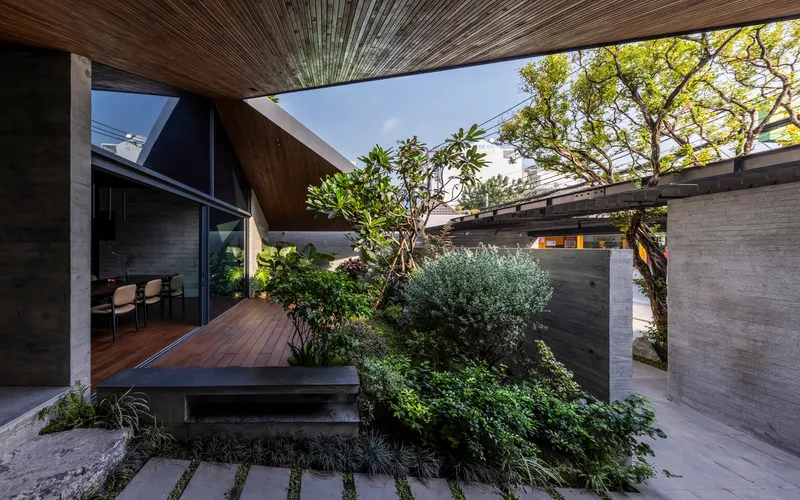 Courtyard deck with planted beds surrounded by board-formed concrete walls and mature trees overhead