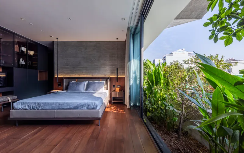 Bedroom with full-height glass doors opening to a planted terrace with tropical foliage