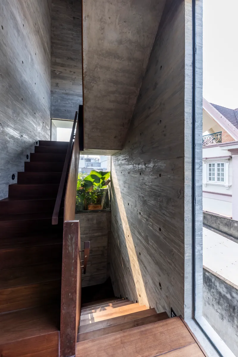 Multi-level concrete staircase with steel balustrade and narrow glazing overlooking neighboring buildings
