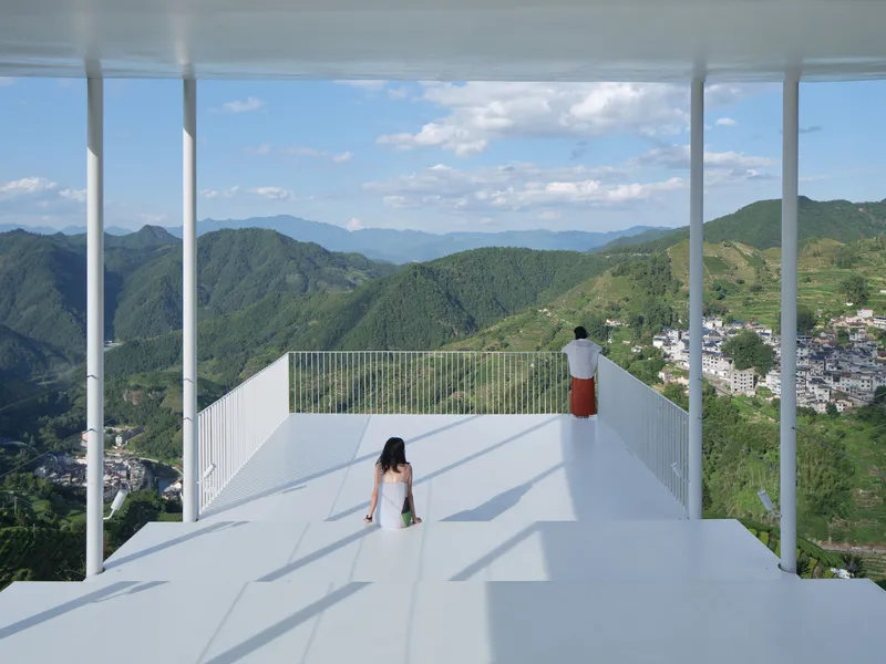 White metal roof deck with slender columns framing views of terraced fields and valley below