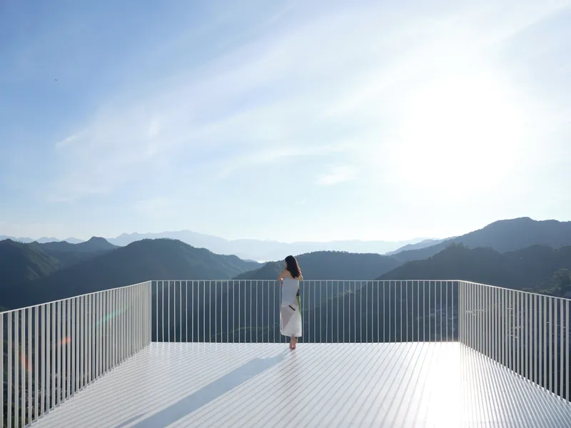 Rooftop terrace with vertical metal louvers overlooking a mountain range on a clear day