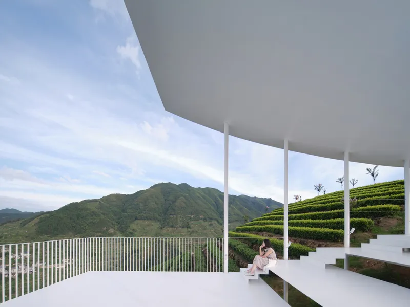 Covered terrace with white columns framing terraced tea fields and distant mountains