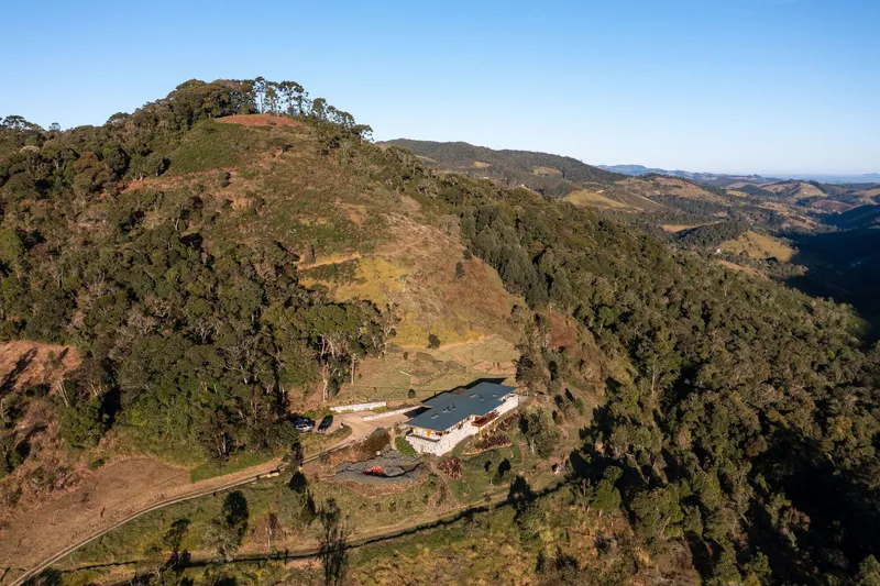 Aerial view of the residence nestled in a valley among forested hills and agricultural fields