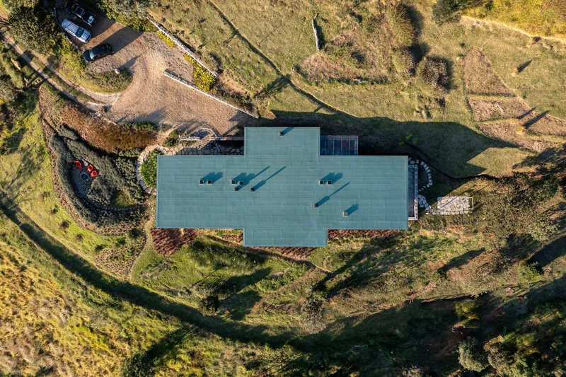 Overhead view of the gray metal roof with four skylights set into terraced hillside landscape