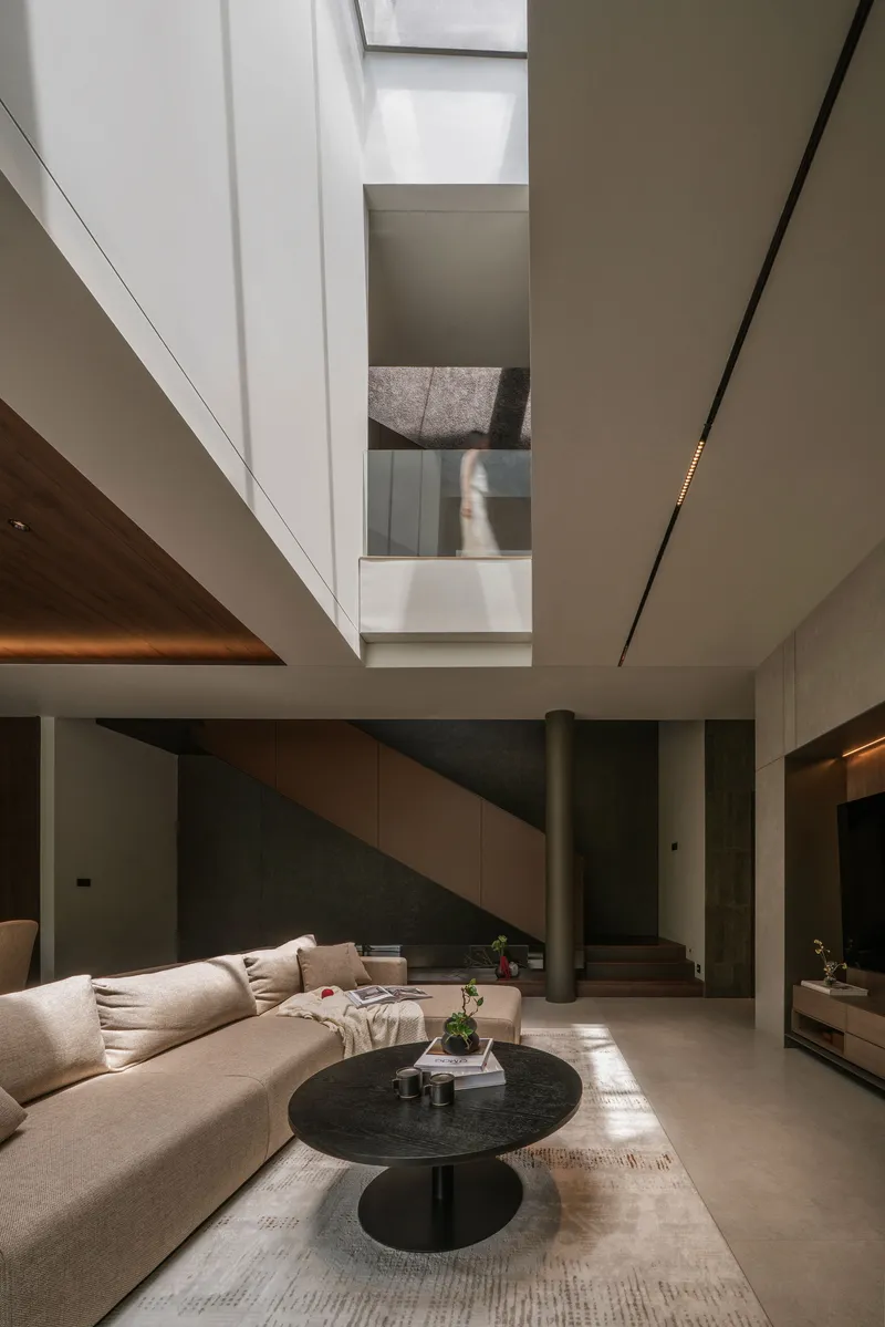 Double height living room with central staircase and skylight above polished concrete floor