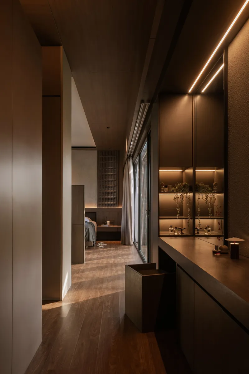 Corridor with integrated lighting along display niches and timber flooring leading toward latticed screens