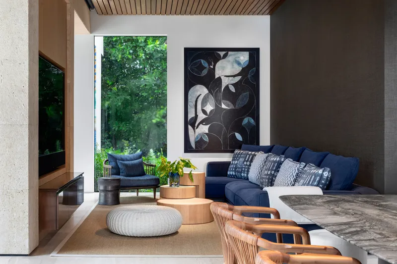 Living room with timber slatted ceiling and tall window opening onto planted terrace