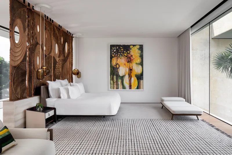 Bedroom with carved timber screen headboard and full-height sliding glass partition