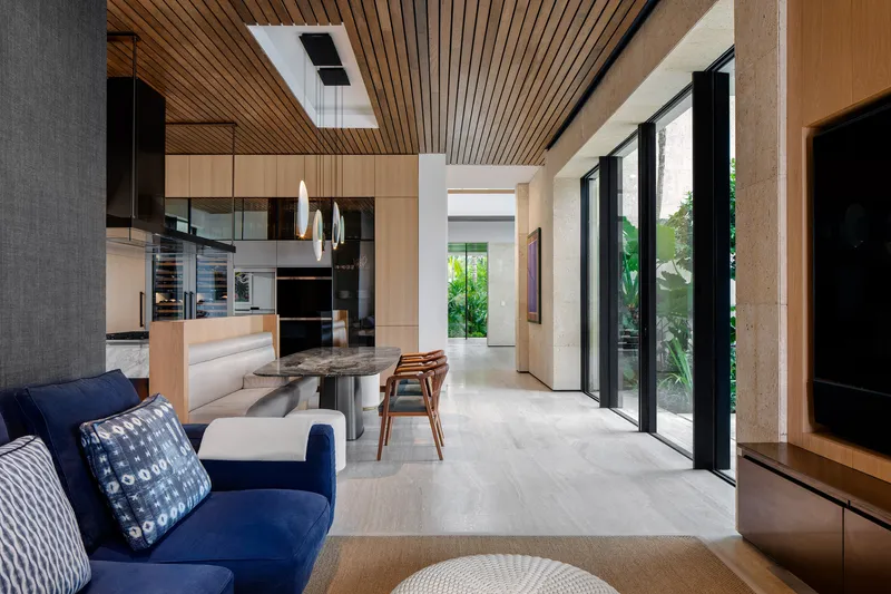 Open-plan living space with slatted timber ceiling and floor-to-ceiling glazing opening to the garden
