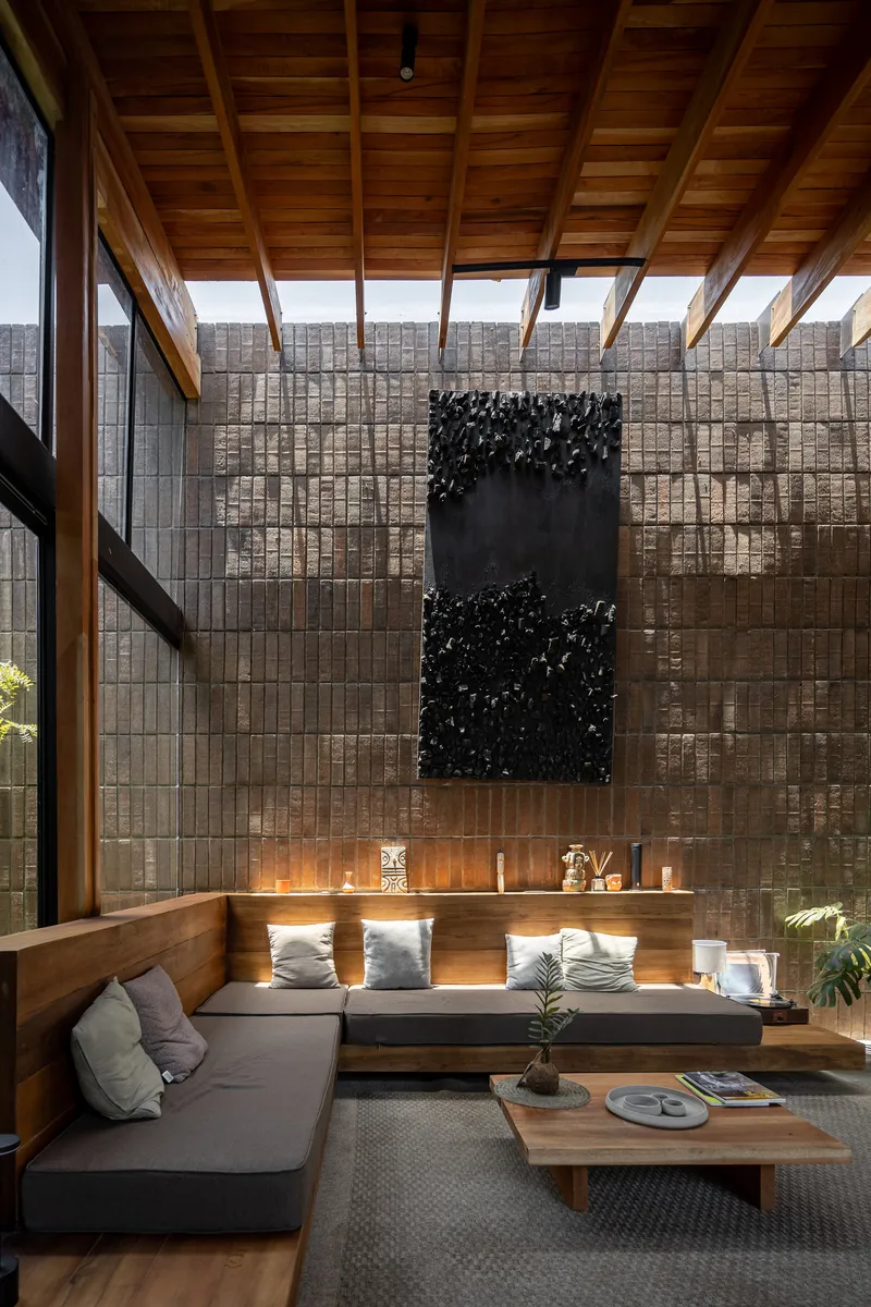 Double-height living room with exposed timber rafters and a decorative panel mounted on the brick wall