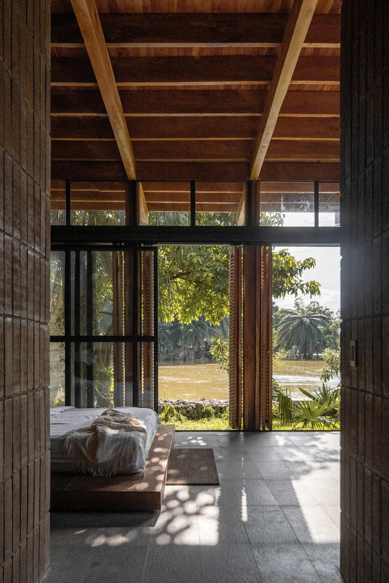 Interior view through brick walls to open timber-framed doorway overlooking garden with afternoon light filtering through
