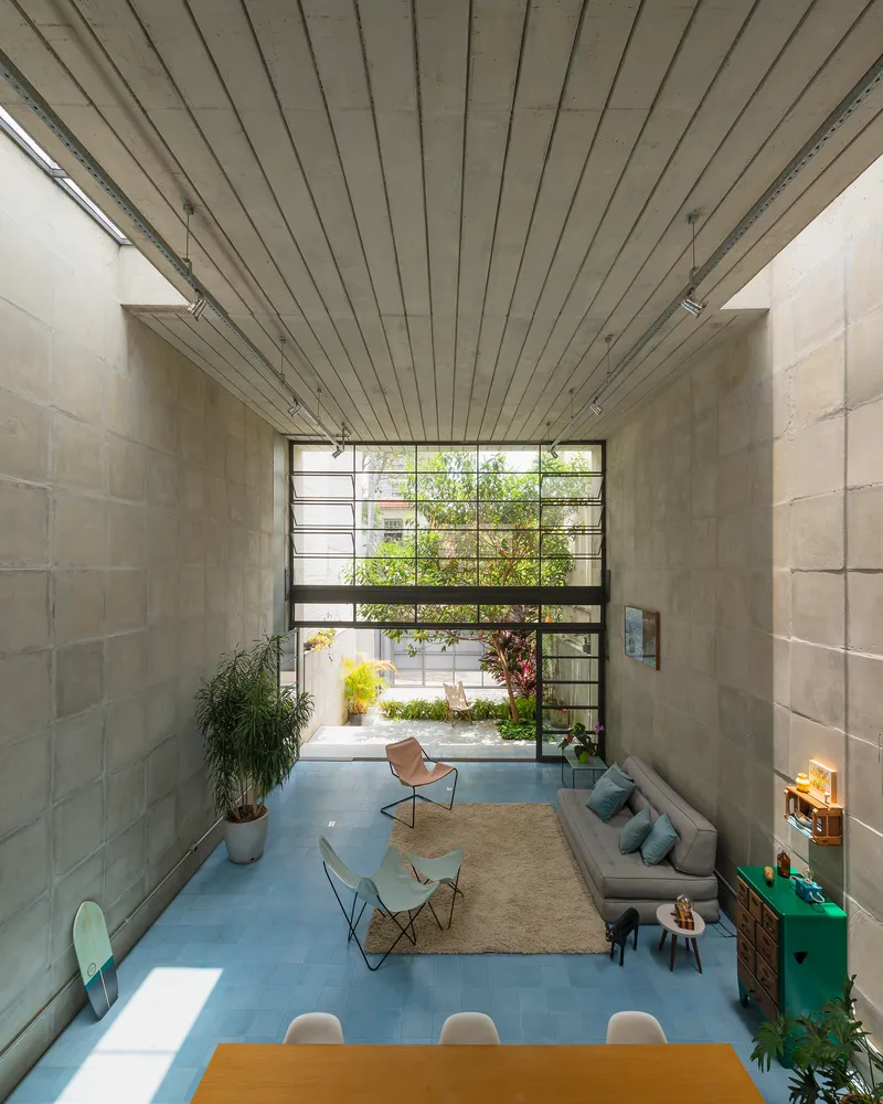View through double-height space toward steel-framed window wall with courtyard garden beyond