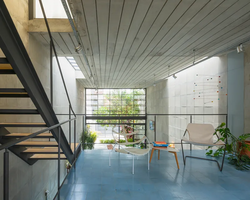 Steel staircase with cable railing ascending beside concrete block wall and clerestory window