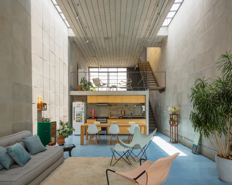 Open-plan interior showing mezzanine with timber stair and kitchen beneath slatted timber ceiling