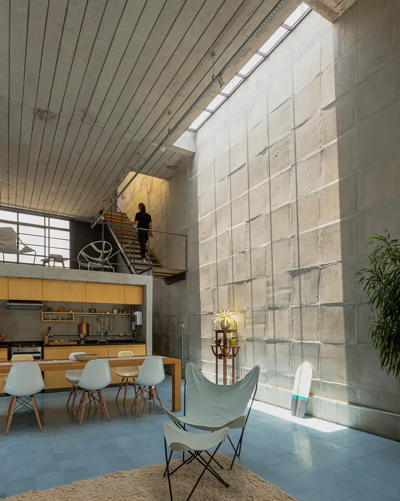 Double-height concrete block wall with figure descending timber stair on mezzanine level