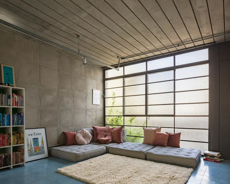 Seating nook with translucent glass block wall, exposed concrete ceiling planks, and built-in bookshelf