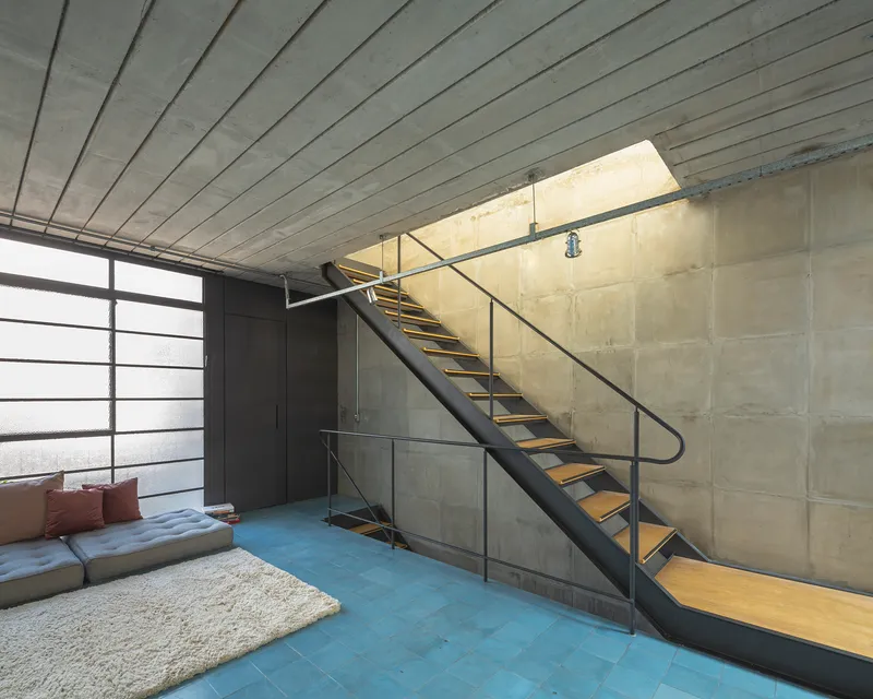 Interior view of metal staircase with wood treads ascending along exposed concrete block wall