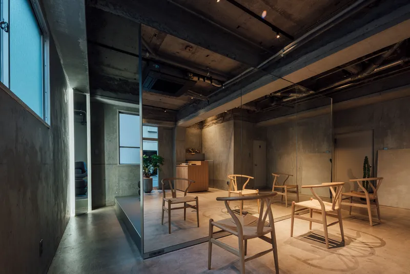 Interior at dusk with track lighting illuminating concrete walls and wooden furniture grouping