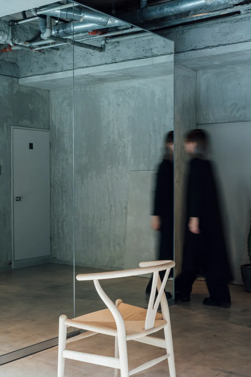 Single wooden chair behind glass panel with two figures in motion blur passing by