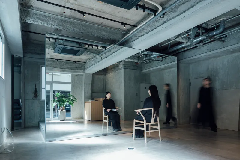 Interior space with glass partition and concrete walls as people in motion pass through the corridor