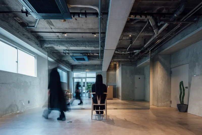 Open floor plan with exposed concrete structure and mechanical systems visible overhead in afternoon light