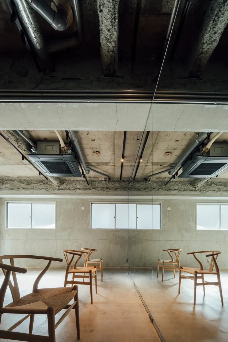 Overhead view showing the suspended white panel bisecting the concrete ceiling above arranged chairs