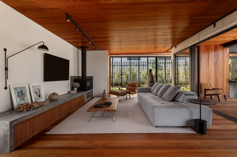 Living room with timber ceiling and concrete media console overlooking a vertical timber screen garden