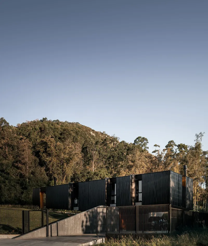 Access ramp and metal railings leading to dark timber-clad structure nestled among eucalyptus trees