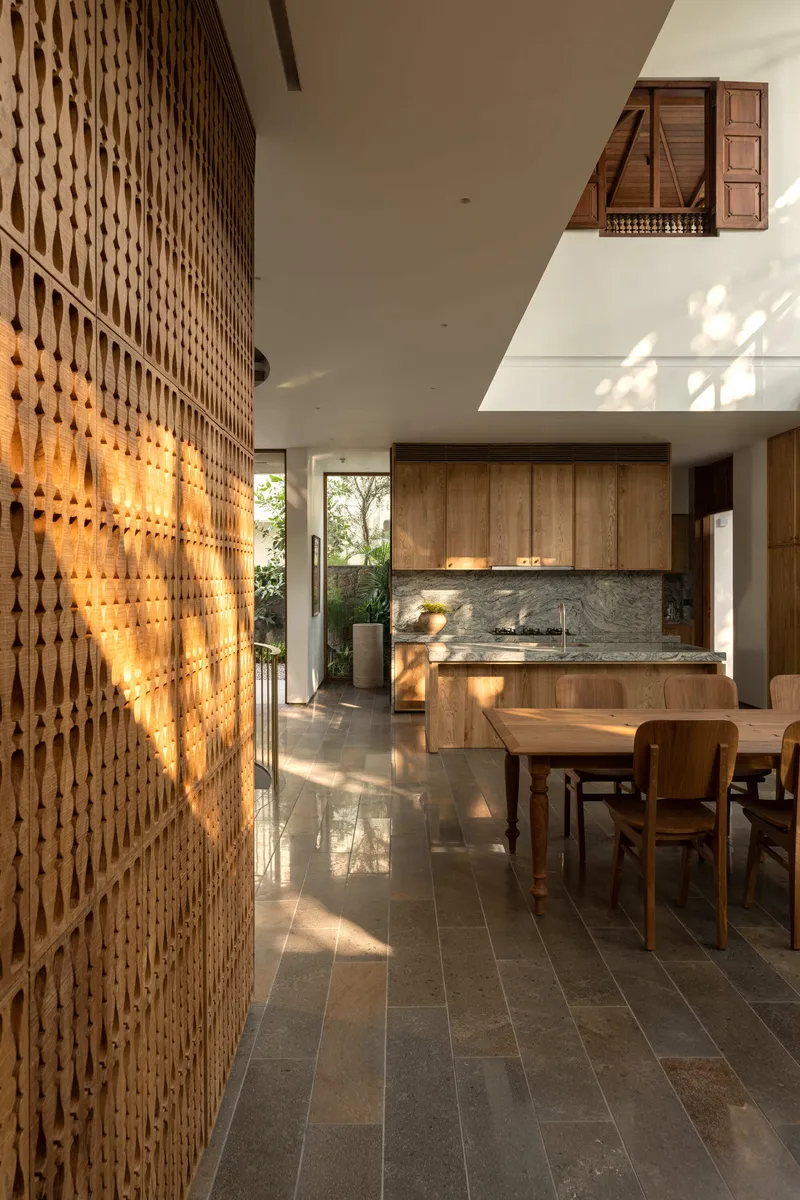 Dining area with perforated timber screen wall filtering sunlight onto polished stone floor