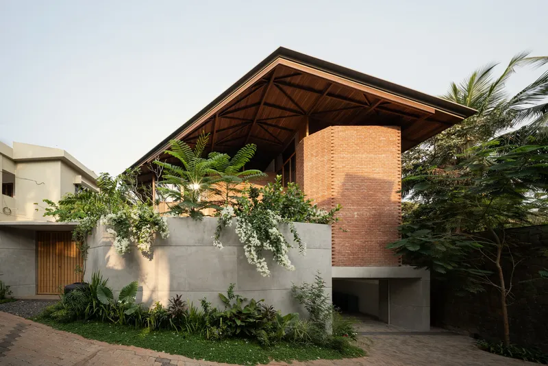 Street view of the concrete and brick facade with planted beds and palm trees