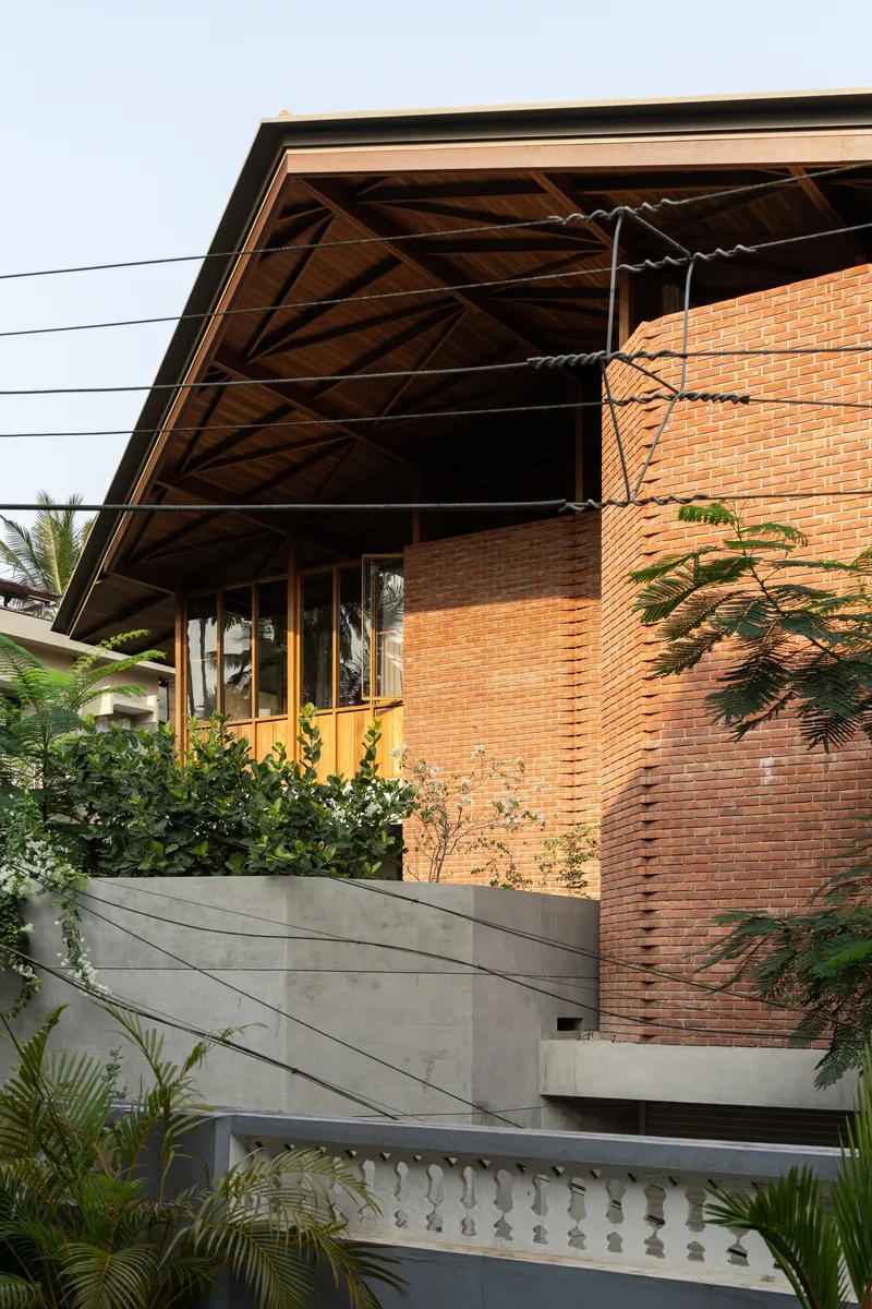 Elevated brick facade with exposed timber truss overhang and planted concrete retaining wall below
