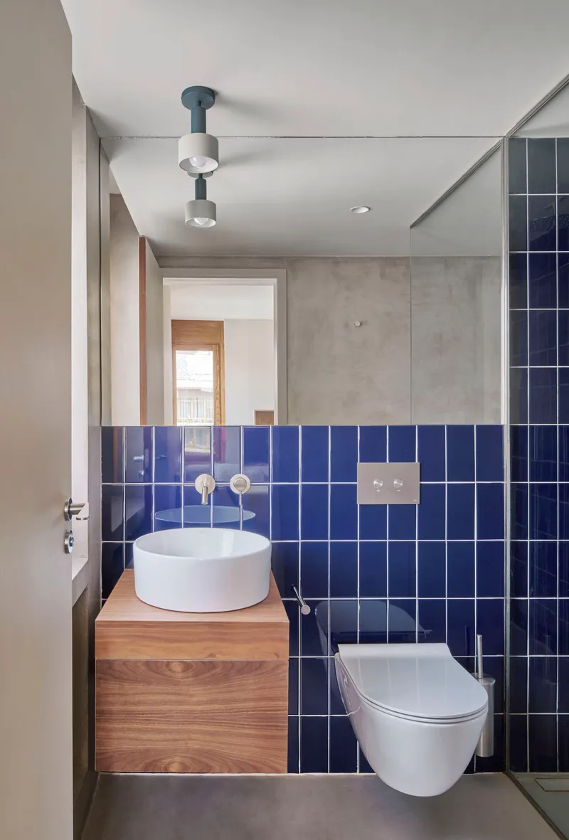 Compact bathroom with cobalt blue square tiles and a round vessel sink on timber vanity