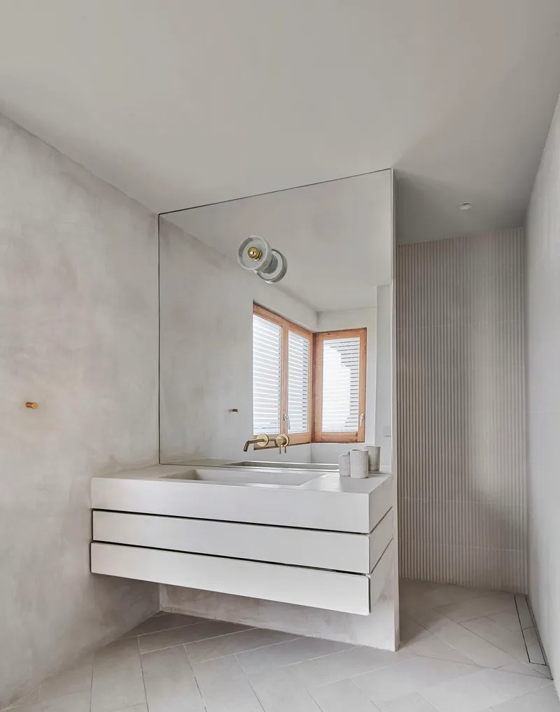 Floating white vanity with integrated sink beneath a large mirror and textured grey plaster walls