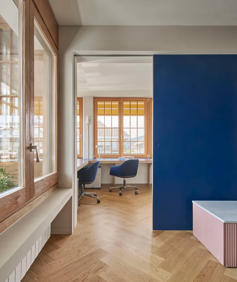 View through doorway to home office with timber-framed windows and navy blue accent wall