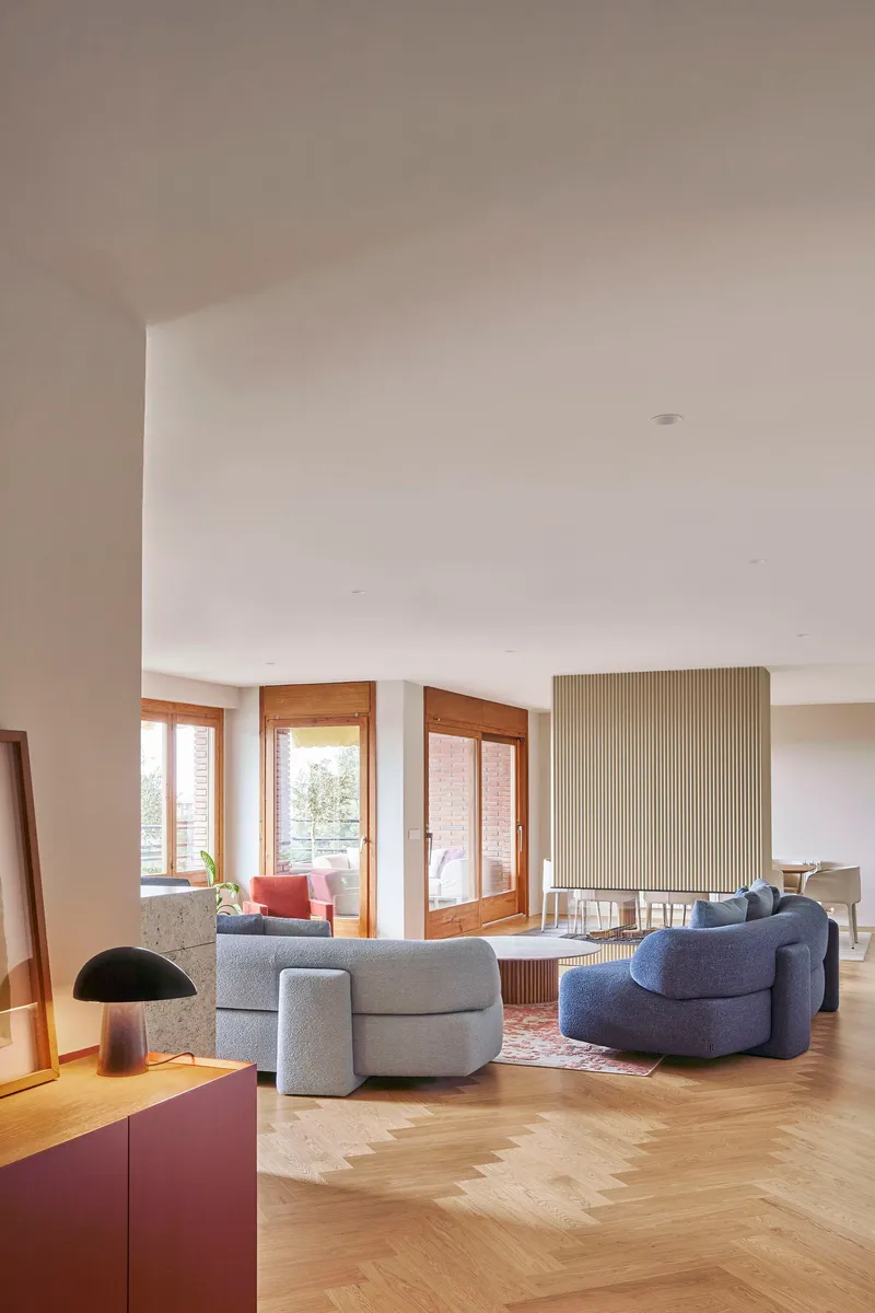 Living room with herringbone oak floor and fluted partition wall in afternoon light