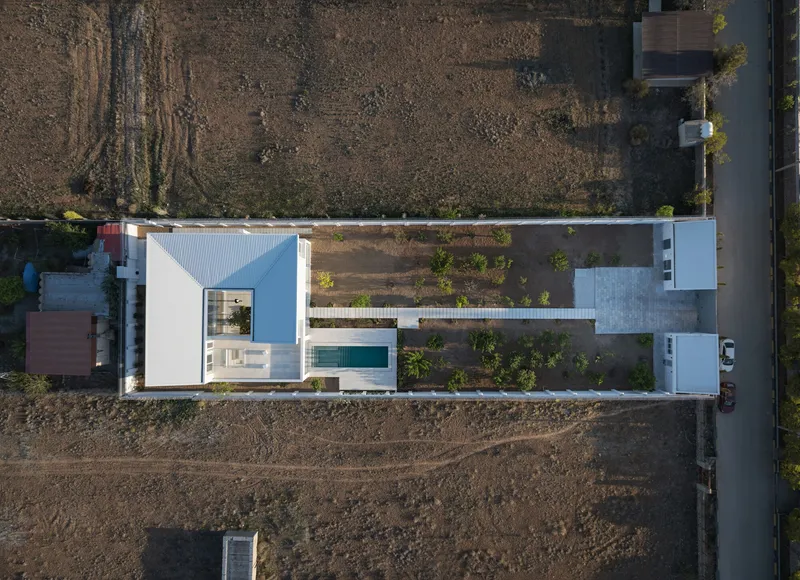 Aerial view of the white volumes arranged around a central courtyard with pool and terraced garden beds