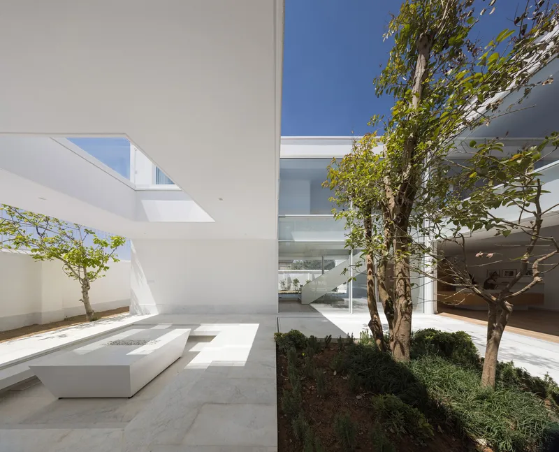 Interior courtyard with limestone paving and angular white planter facing trees and glazed volumes