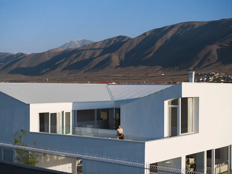 Rooftop terrace with corrugated metal roof panels and a figure standing against distant mountains