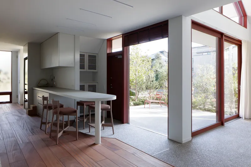 Kitchen and dining area with terrazzo floor threshold and tall mahogany door frames to garden