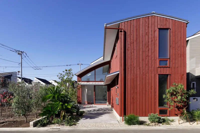Street view of the vertical timber-clad volume with garden beds and overhead power lines