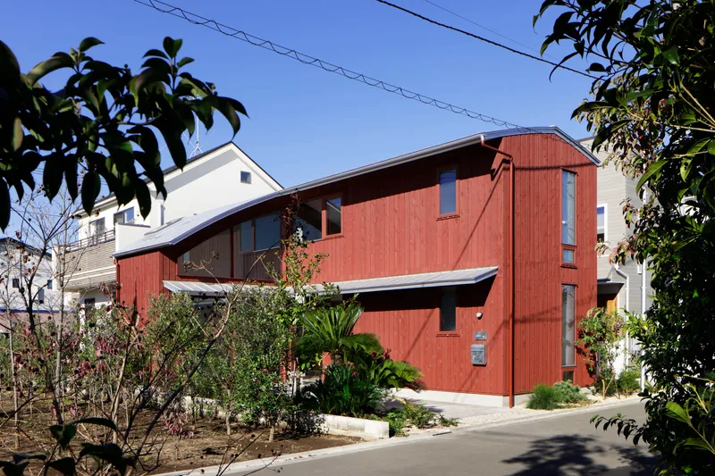 Side elevation showing the curved roof connecting the two-story timber volumes among bare winter trees