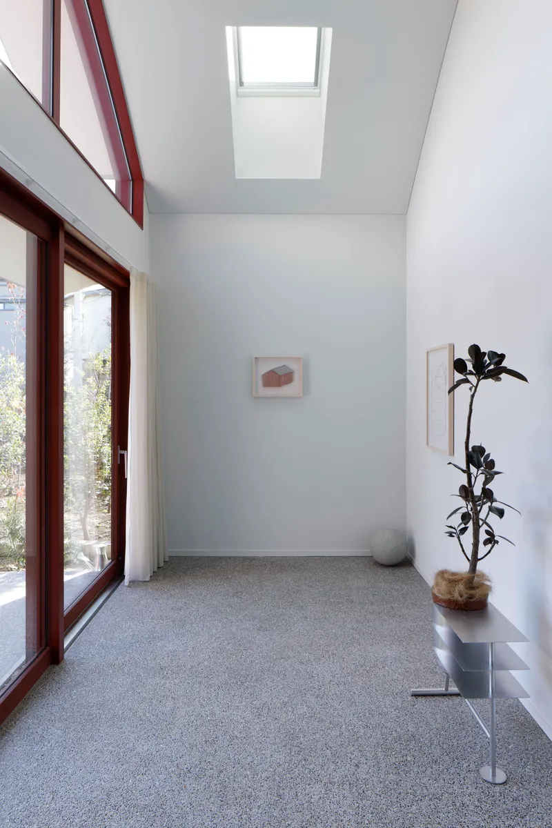 Double-height entry hall with terrazzo floor and skylight above a mahogany-framed glass door