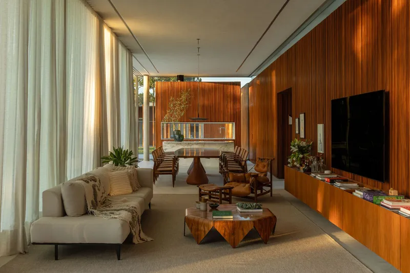 Open-plan living space with sheer curtains and timber cabinetry under a white ceiling plane