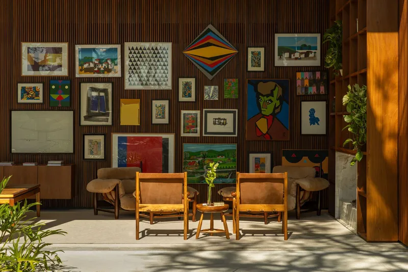 Seating arrangement in front of vertical wood paneling displaying a dense collection of framed artworks