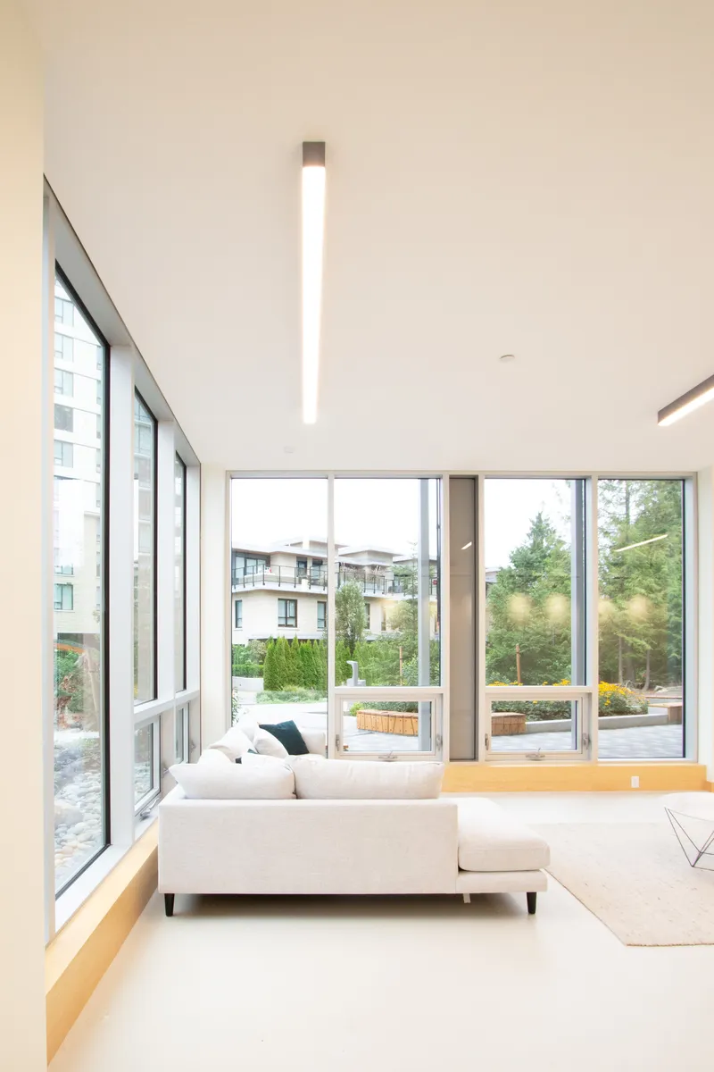 Double-height lounge with sloped ceiling, glazed walls, and a suspended linear pendant fixture
